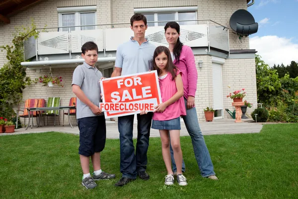 Young family holding a foreclosure sign