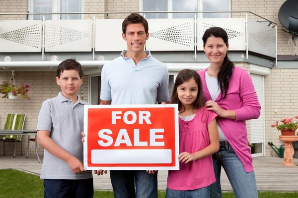Family selling their home holding for sale sign