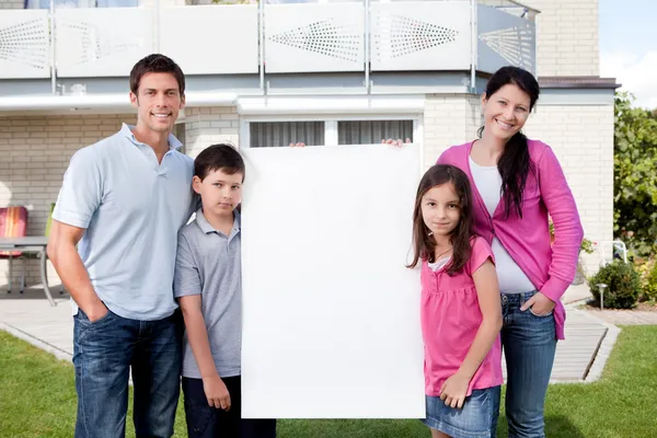 Happy family outside with a blank sign board