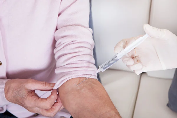 Young Doctor Injecting Vaccine To Senior Woman