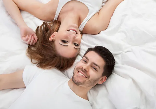 Portrait of happy young couple lying on bed