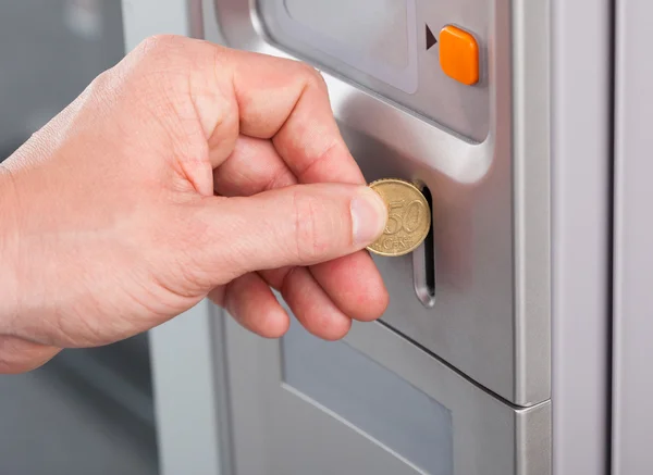 Human hand inserting coin in vending machine