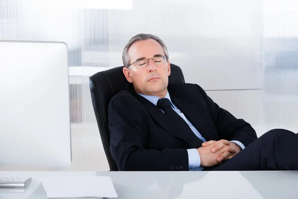 Businessman Sleeping At Desk In Office
