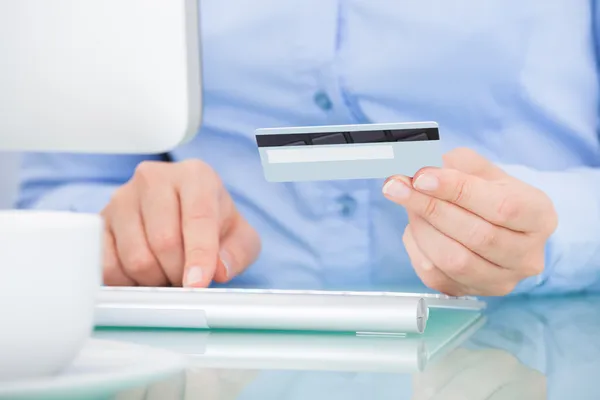 Person Holding Credit Card Using Computer