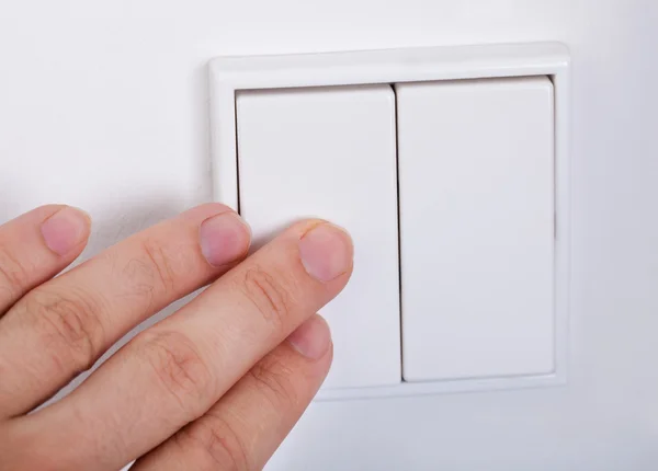 Hand Presses The Light Switch On The Wall