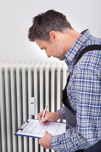 Plumber Taking Readings Of Machine