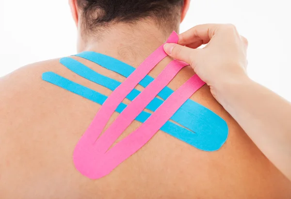 Applying Special Physio Tape On Man\'s Back