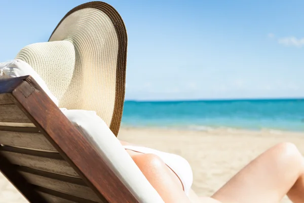 Woman Sunbathing On Deck Chair At Beach