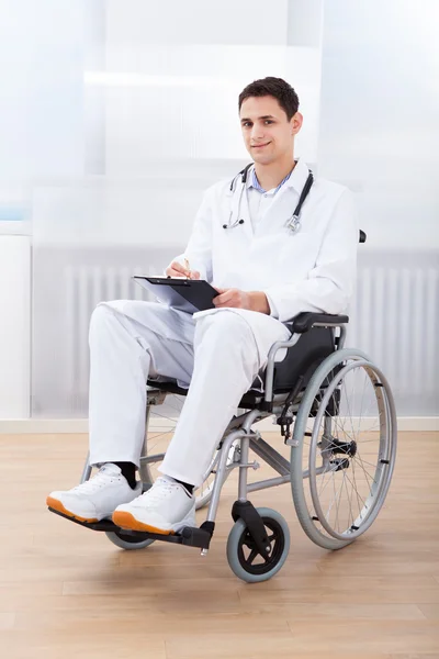 Doctor Witting On Clipboard While Sitting On Wheelchair
