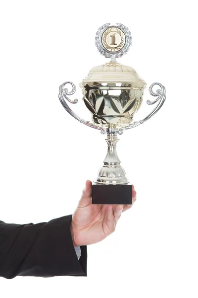 Hand of a businessman displaying a large silver trophy cup