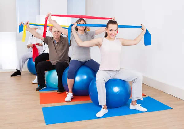 People With Resistance Bands Sitting On Fitness Balls