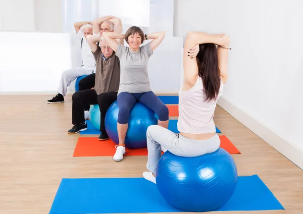 Trainer Training Customers Stretching On Fitness Balls