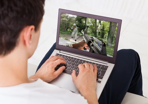 Man Playing Action Game On Laptop At Home