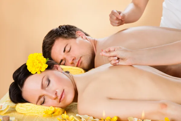 Couple Receiving Acupuncture Treatment At Spa