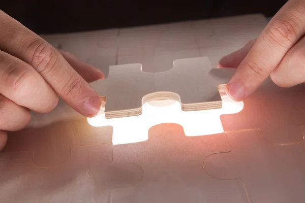 Businessman Fixing Jigsaw Pieces At Desk