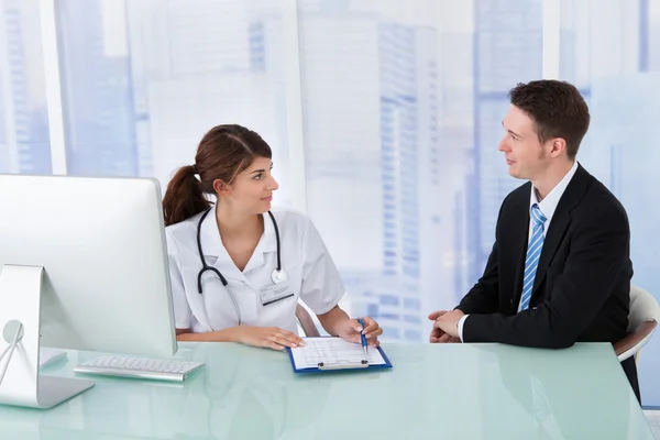 Doctor Showing Report To Businessman