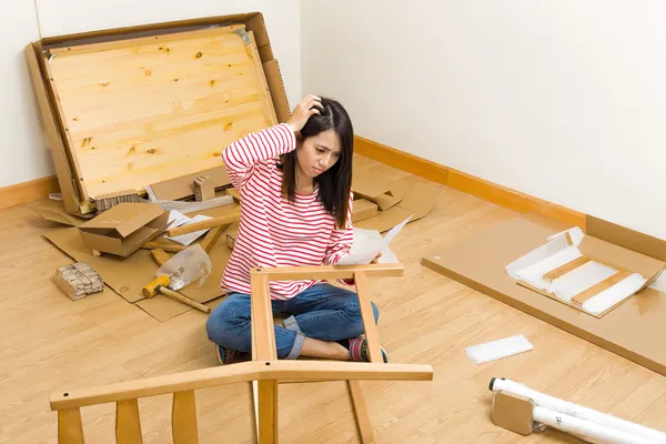 Asian woman assembling new chair with instruction — Stock Photo #36614761