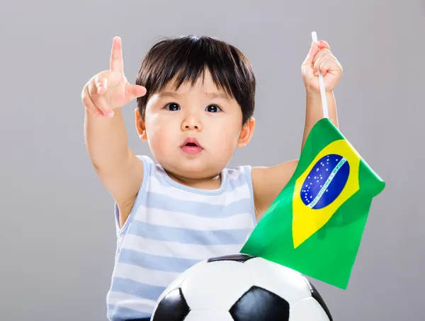 Little boy holding Brazil flag and soccer ball