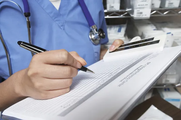 Doctor Writing In Patient's Medical Chart