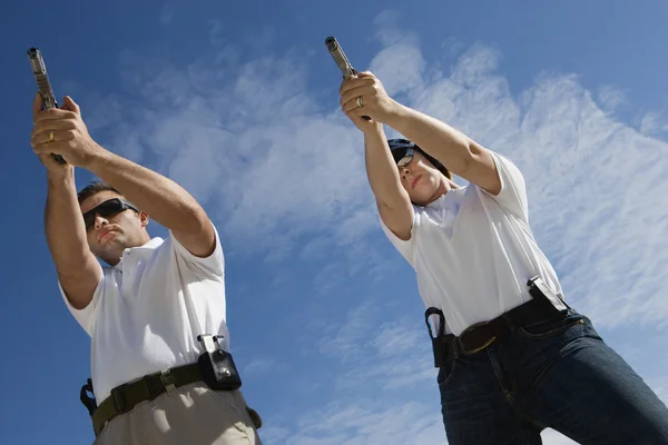 Man And Woman Aiming Hand Guns At Firing Range