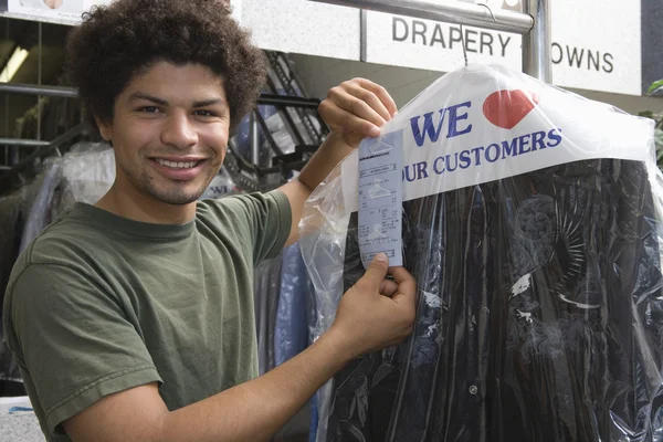 Young Man Holding Receipt In Dry Cleaning Store
