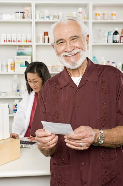 Man Picking Up Prescription Drugs At Pharmacy