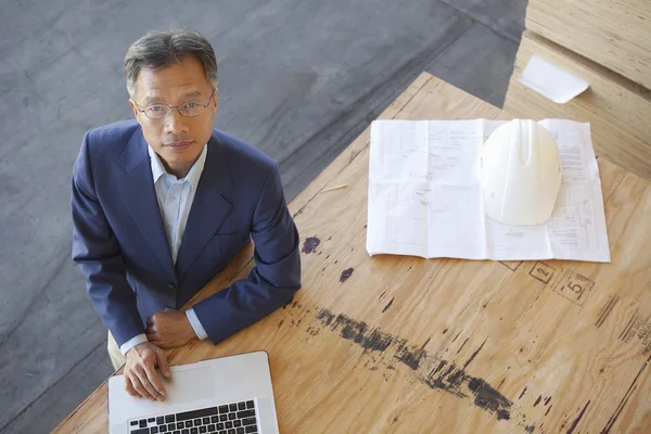 Top view of manager using laptop on plywood in warehouse
