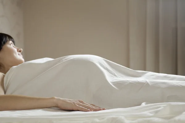 Pregnant woman on bed looking away