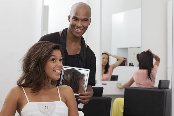 Hairdresser holding a mirror behind young woman