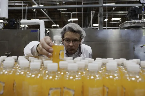 Quality control worker checking juice bottle on production line