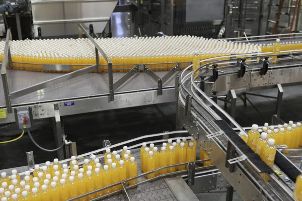 Orange juice bottles on conveyor belt in bottling plant