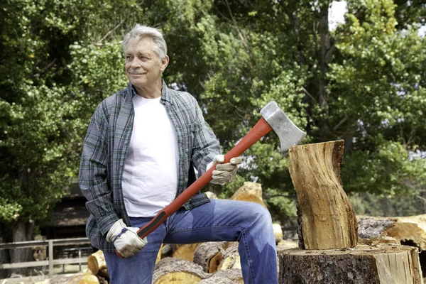 Senior lumber jack holding an axe and looking away