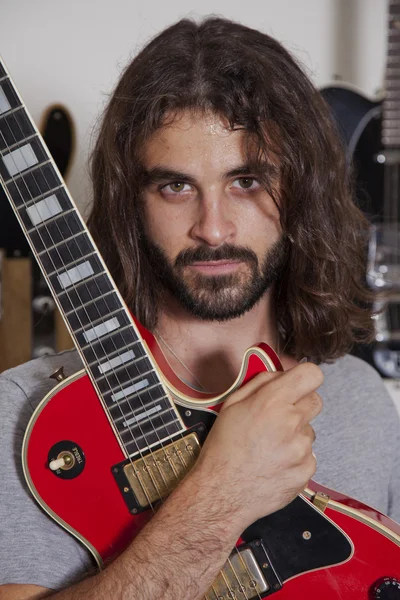 Portrait of serious young musician holding guitar