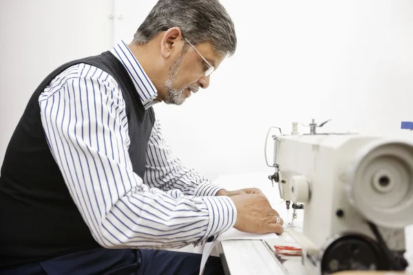 Profile of middle aged tailor using sewing machine