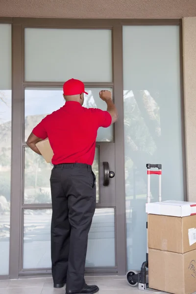 Rear view of a delivery man knocking on door