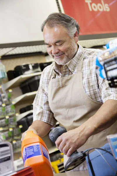 Happy mature salesperson using barcode reader at checkout counter in hardware counter — Stock Photo #21881023