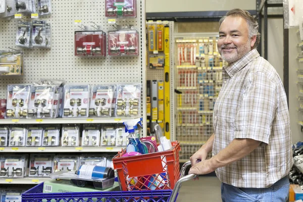 Side view portrait of a happy mature man with shopping cart in hardware store — Stock Photo #21881111