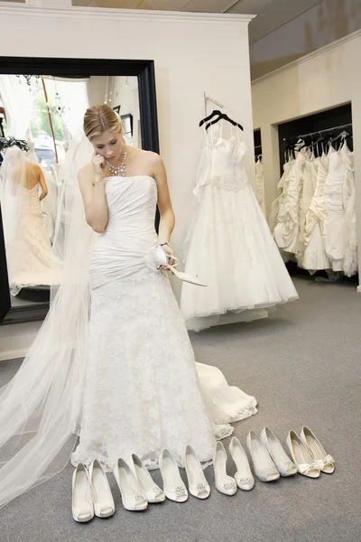 Beautiful young woman confused while selecting footwear in bridal boutique