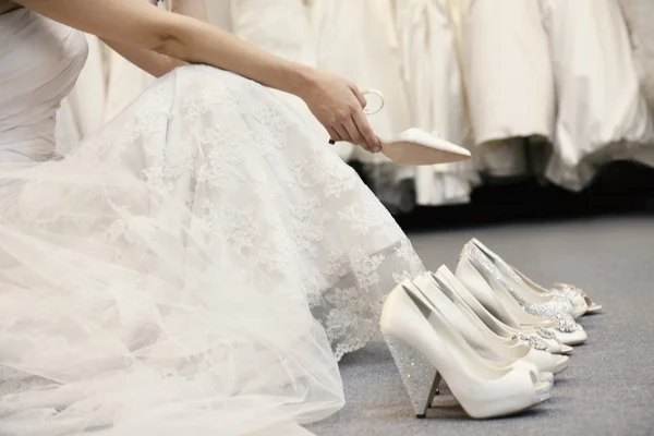 Low section of woman sitting with variety of footwear in bridal boutique