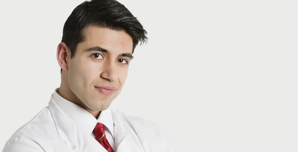 Close-up portrait of a handsome Indian male doctor smiling over light gray background