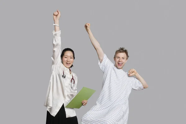 Portrait of doctor and patient cheering up with raised arms