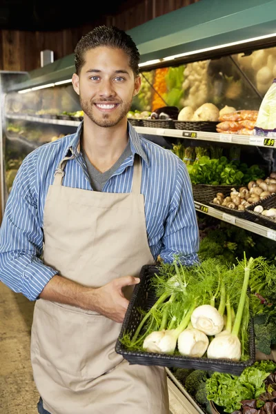 Portrait of a happy man with basket full of green onion in supermarket