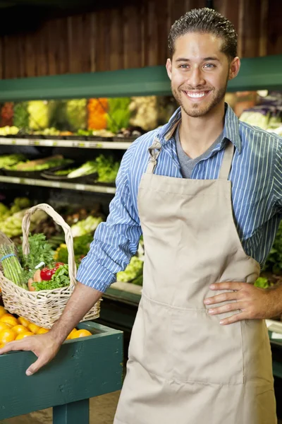 Handsome young sales clerk standing near stall in supermarket