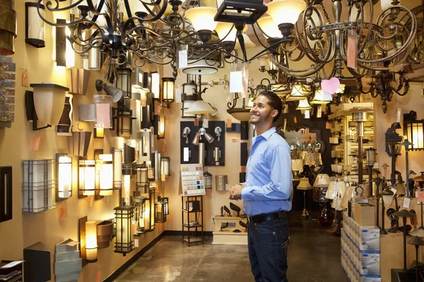 Happy young man browsing for lights fixture in store — Stock Photo #21899589