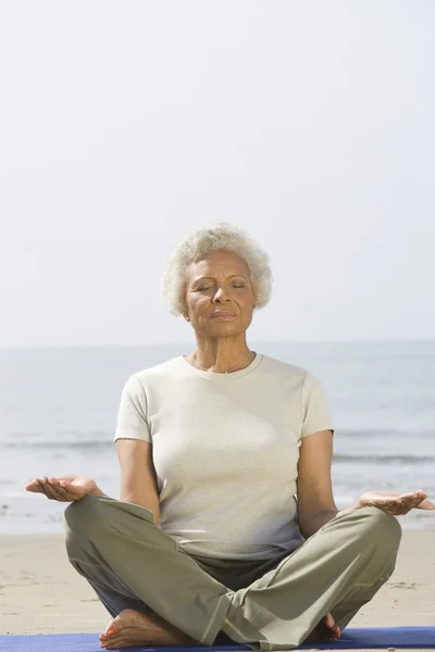 Senior Woman Meditating At Beach