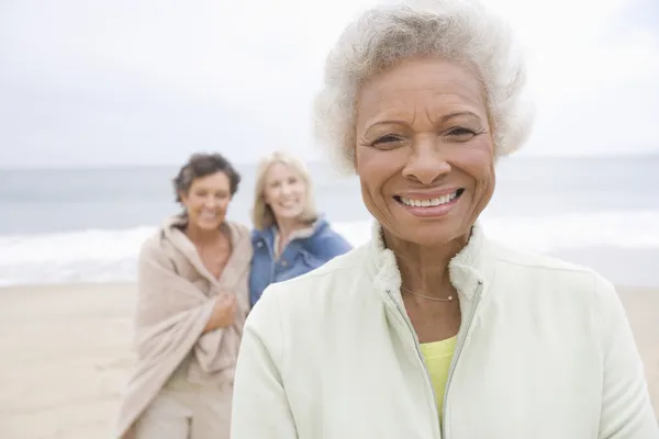 Senior Woman In Fleece Jacket With Friends On Beach