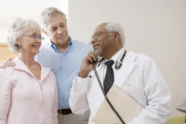 Doctor Looking At Patients While Using Landline Phone