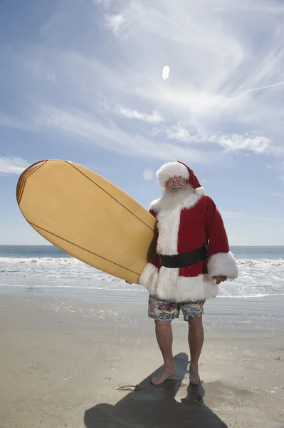 Santa Claus Holding Surfboard On Beach