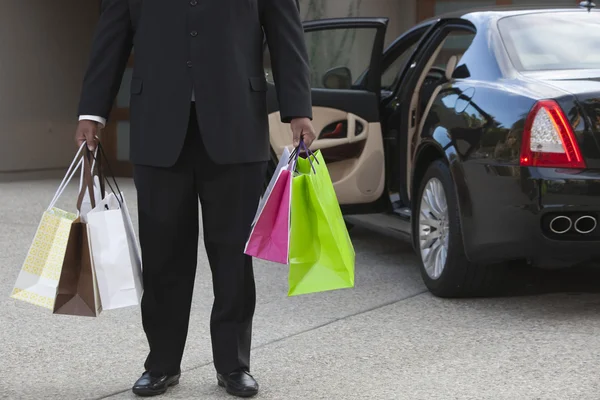 Chauffeur With Shopping Bags In Driveway
