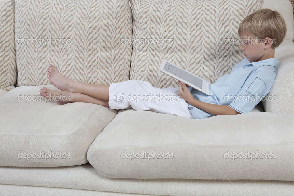 boy using digital tablet on sofa stock photo boy using digital tablet on sofa stock photo
